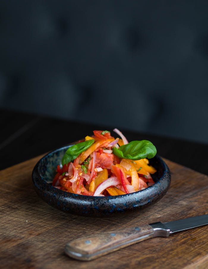 Sliced Tomato With Green Vegetables in Brown Saucer
